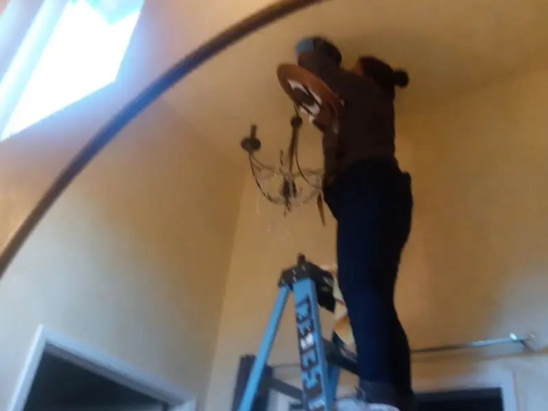 Electrician installing a chandelier in a Homeland residence